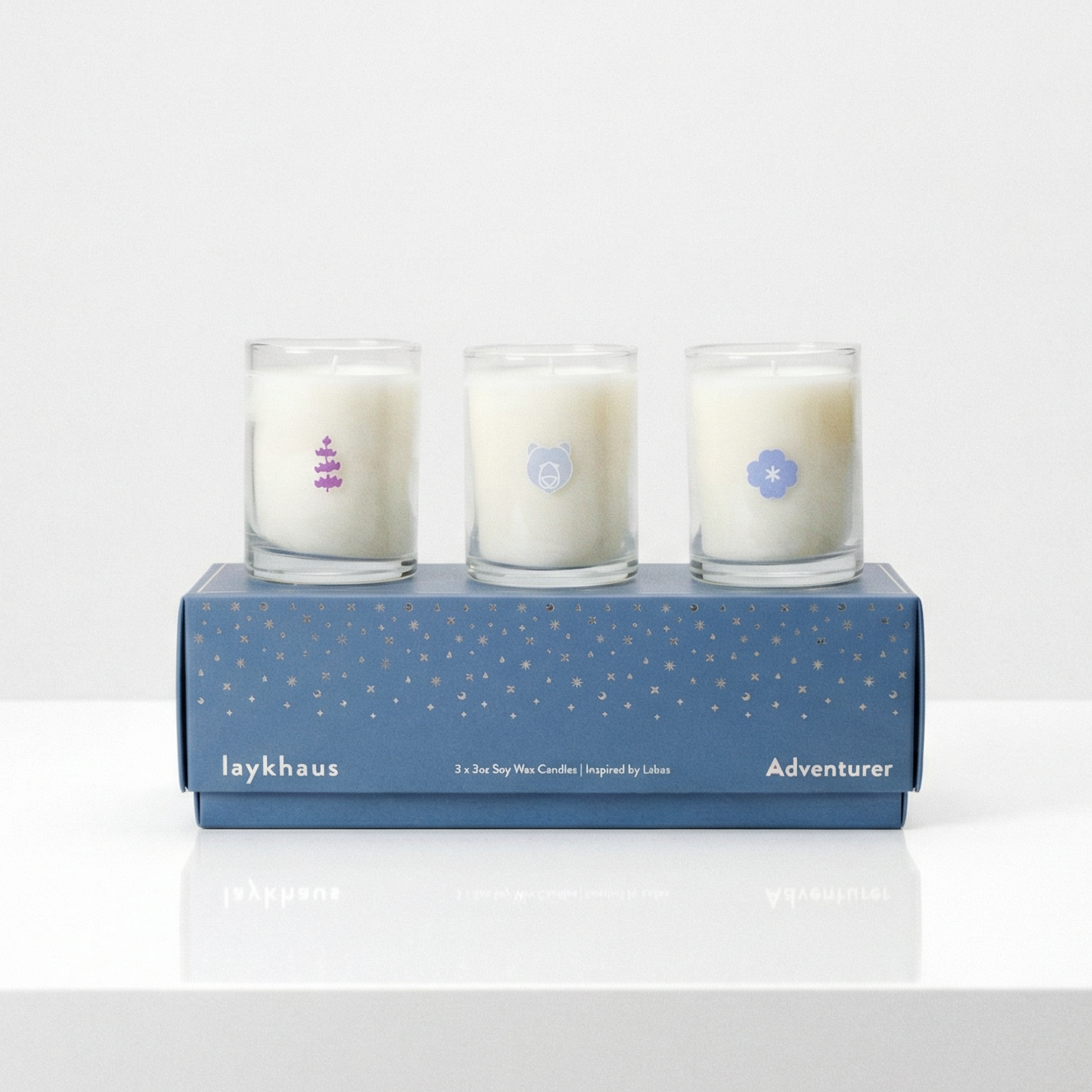 Three candles in a blue box on a white surface with a light gray background