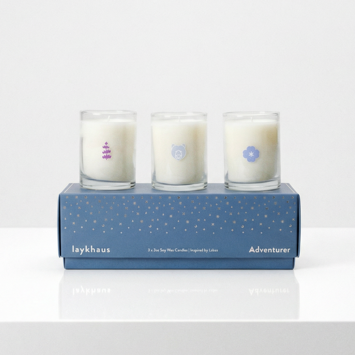 Three candles in a blue box on a white surface with a light gray background