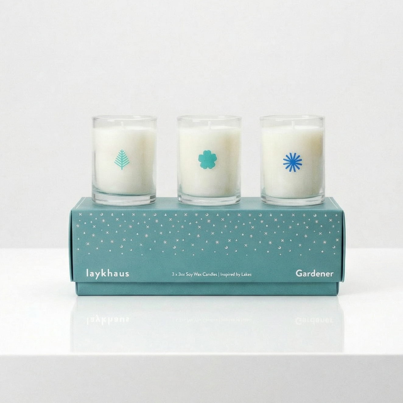 Three candles in a box with a brand logo on a white surface