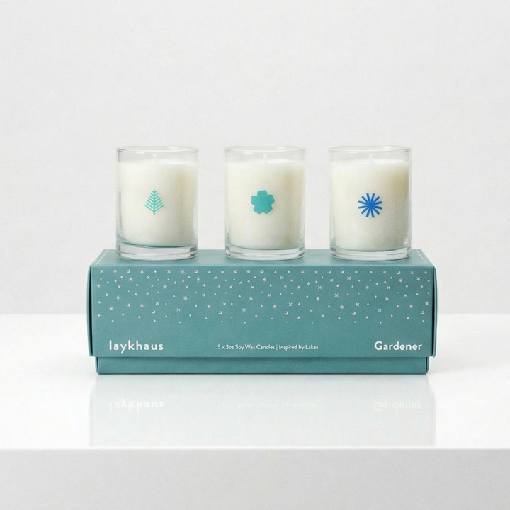 Three candles in a box with a brand logo on a white surface